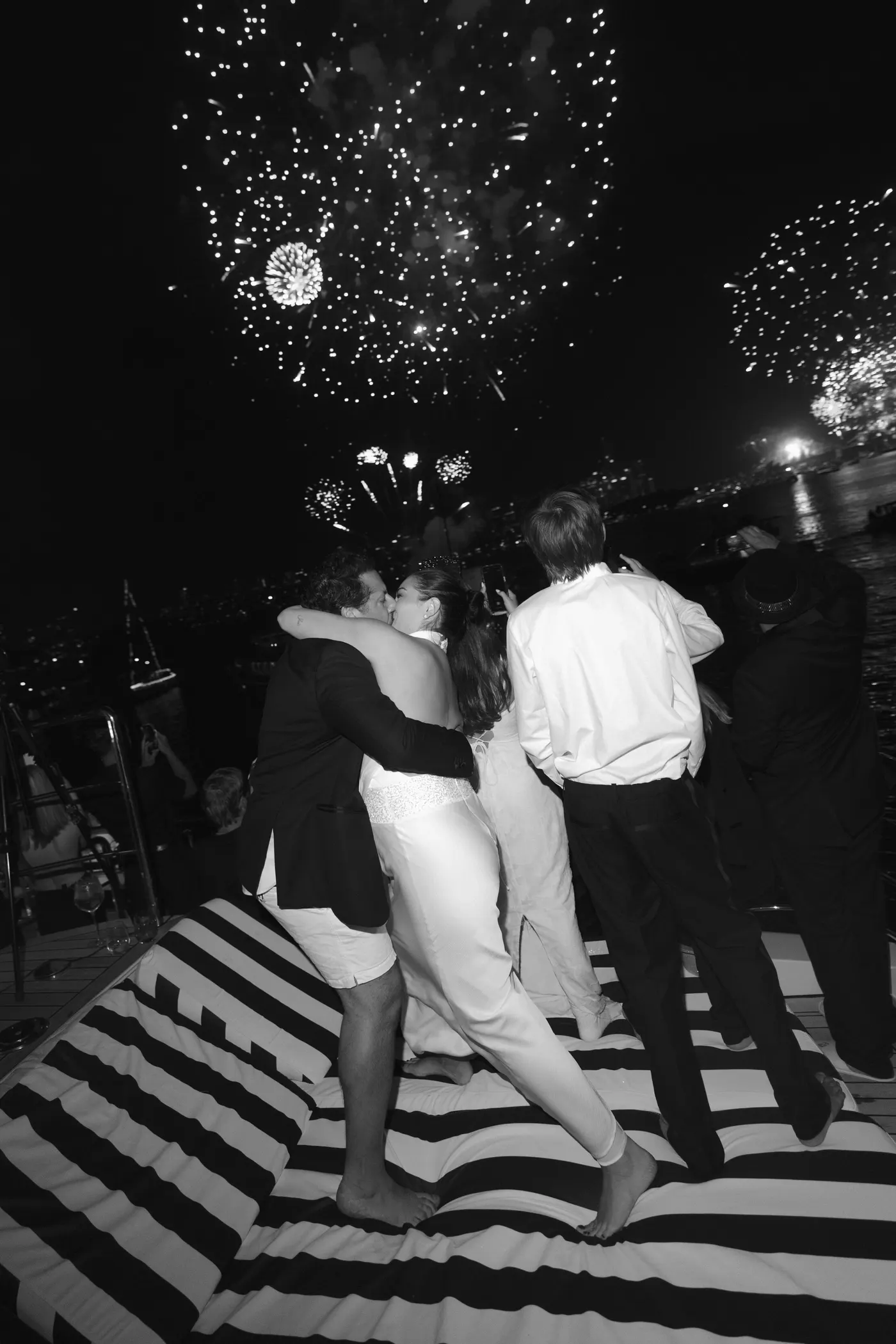 Black and white: a couple kissing on the sunpads as the fireworks go off overhead