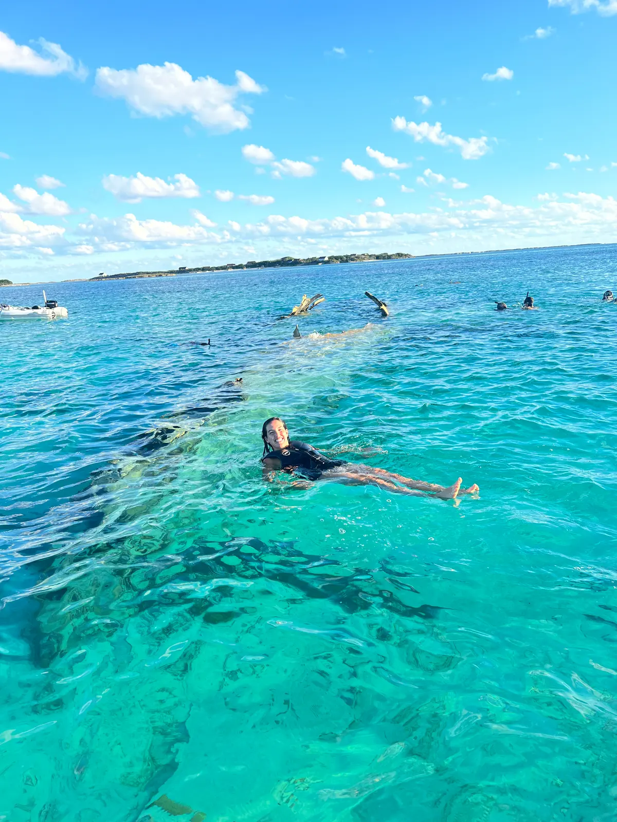 Ellie floating over the plane wreck in the shallows off Norman's Cay, snorkellers behind